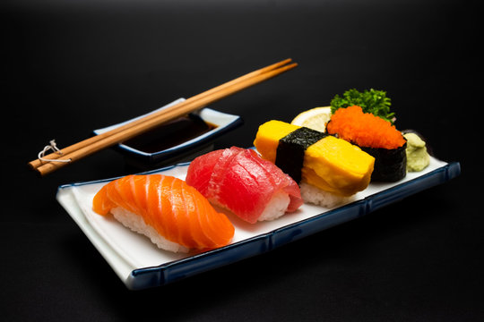 Sushi salmon & tuna sushi shrimp and wasabi on the white plate. on the black table