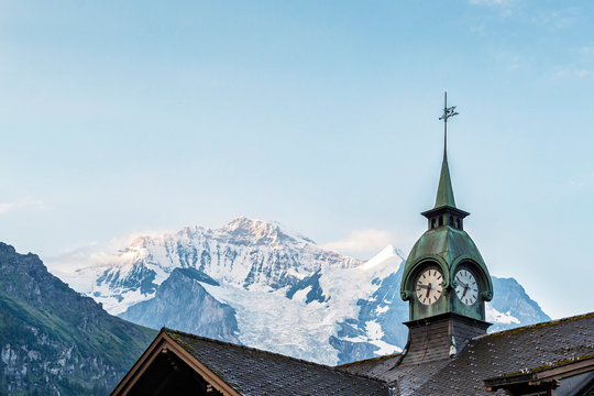 Clock Tower in Switzerand with beautiful snow covered Jungfrau Mountain in the Background.