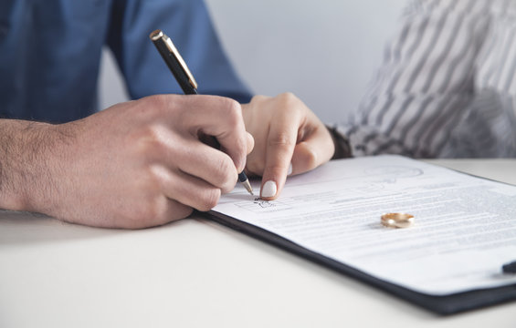 Couple with divorce contract and ring on desk. Divorce