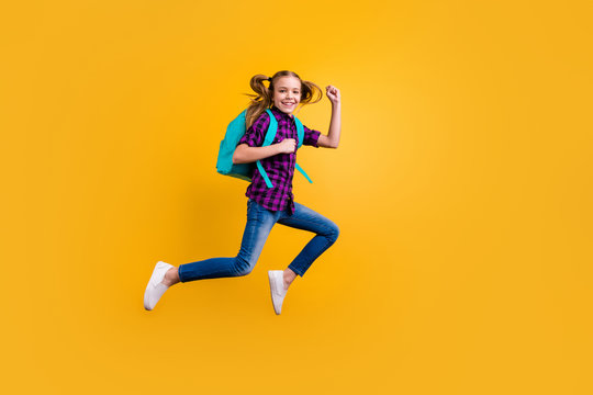 Full length side photo of little pupil jump high glad return school wear casual checkered shirt jeans denim isolated yellow background
