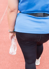 Girl in blue sportswear, black pants.Water bottle in hand.