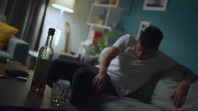 Drunk man drinking alcohol and falls from sofa