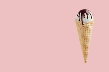 White ice cream in crisp waffle cone with chocolate sauce on pastel pink background, mock up, summer food.