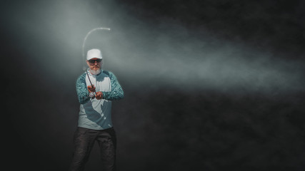 Fisherman performs casting spinning. Isolated image on a dark background with a haze.