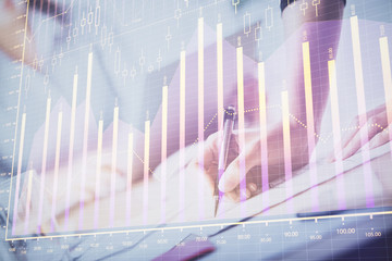 A woman hands writing information about stock market in notepad. Forex chart holograms in front. Concept of research. Double exposure