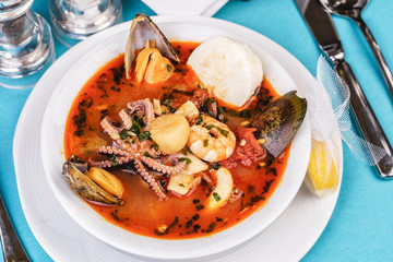 Tomato soup made from chicken, rings of colmar, octopus, mussels and vegetables according to a Mediterranean recipe
