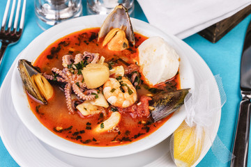 Tomato soup made from chicken, rings of colmar, octopus, mussels and vegetables according to a Mediterranean recipe