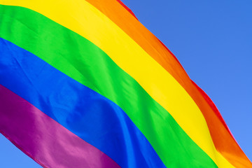 Gay rainbow flag waving in the wind in a clear blue sky