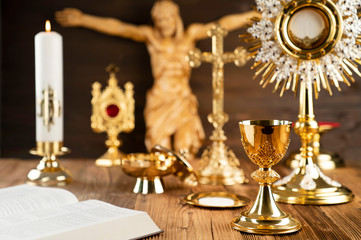 Catholic concept background. The Cross, monstrance and golden chalice on the rustic wooden altar.