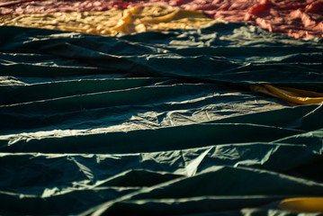 Hot air balloon textiles laying on a green grass. European balloon festival in Spain. International meeting of hot air balloons and flying competition. 