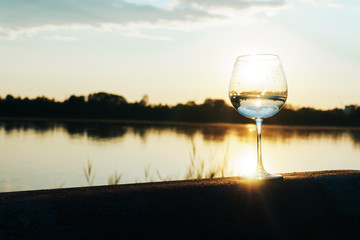 Obraz premium a glass of water on the background of the river and the sunset