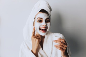 cream on her face, mask on the face, a towel on his head, problem skin.Attractive young woman...