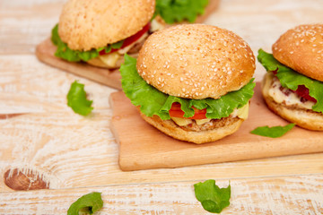 Craft beef burger  on wooden table on light background. Street food, fast food. Homemade juicy burgers with cheese and  on the wooden table. Copy space.
