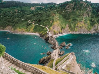 Picturesque picturesque road winding stairs to the island Gaztelugatxe on the coast of the Bay of Biscay and looks at the mountain. Spain, Basque Country