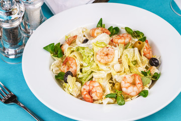 Mediterranean salad. Cabbage, tomatoes, shrimps, olives, olives, basil and rosemary, seasoned with olive oil