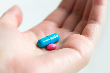 Blue and pink pill capsule on the female palm on white background. Antidepressant pills in female...
