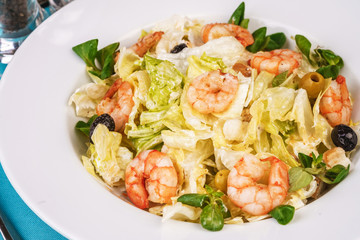 Mediterranean salad. Cabbage, tomatoes, shrimps, olives, olives, basil and rosemary, seasoned with olive oil