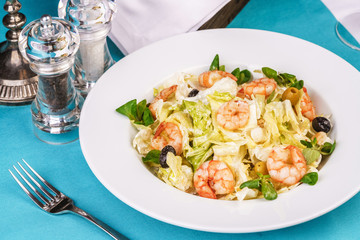 Mediterranean salad. Cabbage, tomatoes, shrimps, olives, olives, basil and rosemary, seasoned with olive oil