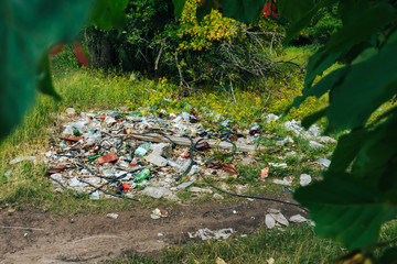 scattered trash in a green summer forest, environmental pollution