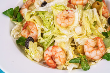 Mediterranean salad. Cabbage, tomatoes, shrimps, olives, olives, basil and rosemary, seasoned with olive oil