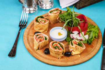 Mediterranean snack. Rolls with salmon, greens, cucumber and vegetables with cream sauce