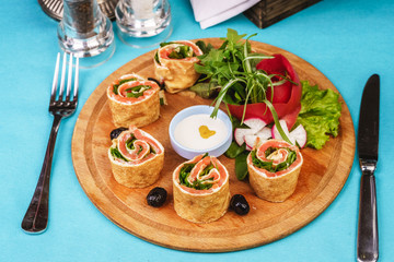 Mediterranean snack. Rolls with salmon, greens, cucumber and vegetables with cream sauce