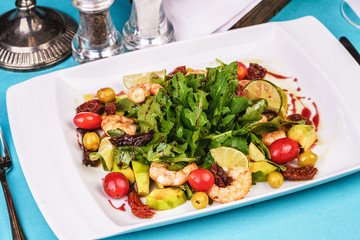 Mediterranean salad with grilled shrimps, cherry tomatoes, arugula, greens, avocado, lime, olives, balsamic sauce