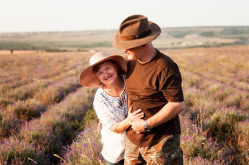 Portrait of happy senior couple in hat on a lavender field.