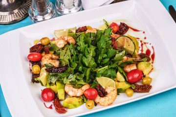 Mediterranean salad with grilled shrimps, cherry tomatoes, arugula, greens, avocado, lime, olives, balsamic sauce
