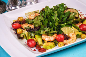 Mediterranean salad with grilled shrimps, cherry tomatoes, arugula, greens, avocado, lime, olives, balsamic sauce