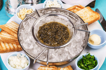 Mediterranean caviar appetizer on ice, toast, butter, greens and a set of sauces