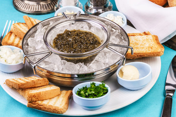 Mediterranean caviar appetizer on ice, toast, butter, greens and a set of sauces