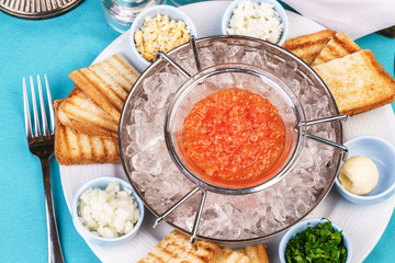 Mediterranean red caviar appetizer on ice, toast, butter, and a set of sauces