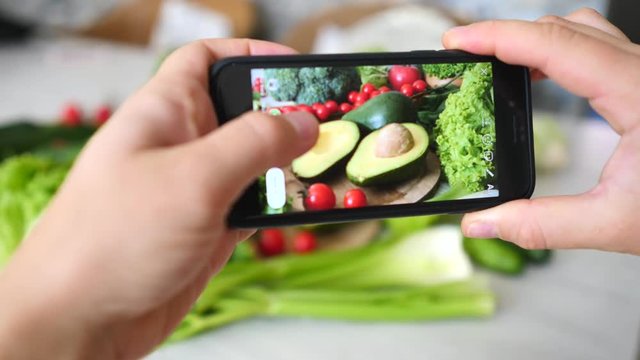 Woman Hands Takes Photo Of Healthy Organic Food On Table With Phone. Smartphone Photo For Social Networks Post.