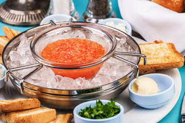 Mediterranean red caviar appetizer on ice, toast, butter, and a set of sauces