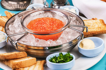 Mediterranean red caviar appetizer on ice, toast, butter, and a set of sauces