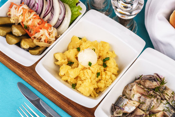 Mediterranean snack of puree, pickled herring, quail eggs, pickled cucumbers, onion rings, pickled cabbage, onions and greens
