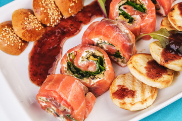 Mediterranean salmon rolls with cheese and greens in chili sauce, served with pancakes and buns