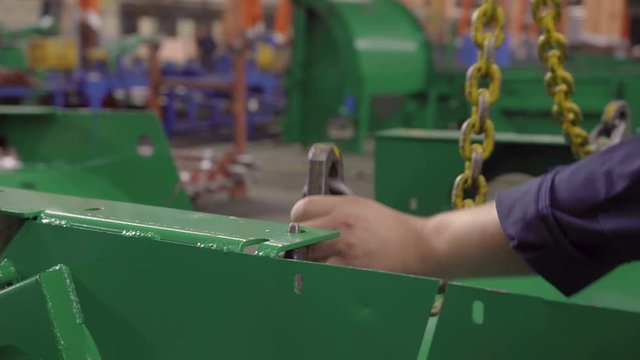 Closeup of Steadicam shot of men working without personal protective equipment, worn-out catchy metal hook detail green at an engineering plant. The concept of safety when performing lifting