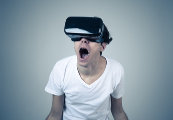 Portrait of cheerful and shocked young man wearing 360 Virtual Reality headset exploring 3D world