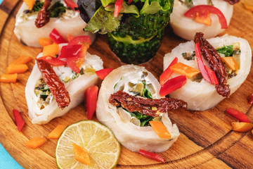 Seafood, Mediterranean cuisine. Vegetable rolls from sea fish with greens, cucumber, lemon and chili. Japanese food