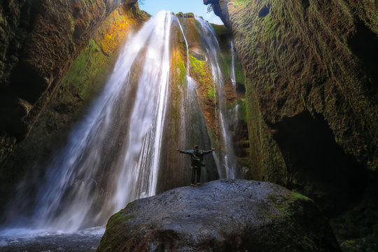 Traveler stunned by Gljufrabui waterfall cascade in Iceland.