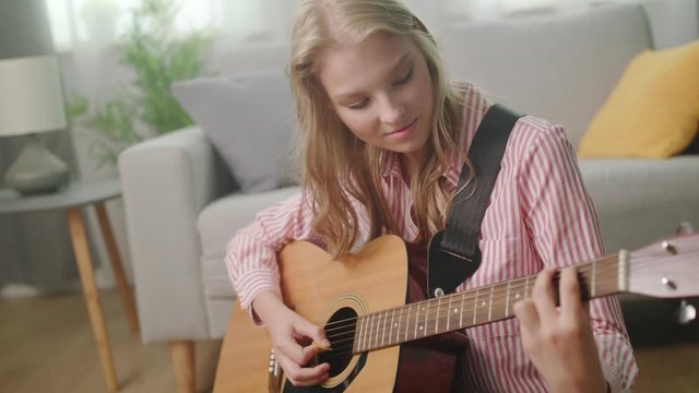 Beautiful woman playing guitar in his living room