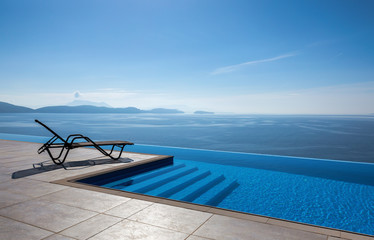 Fototapeta na wymiar Beautiful view of the sea. In the foreground an infinity pool with a lounger 