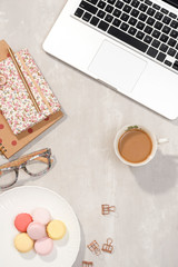Workspace with laptop, notebook, glasses, cup of coffee and lisianthus flowers on gray background. Top view feminine office table desk. Freelancer working place