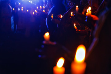 Many people in a crowd holding lit candles at night