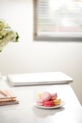 Home office desk with beautiful hortensia bouquet, macaron in front near window. Blog, website or social media concept .