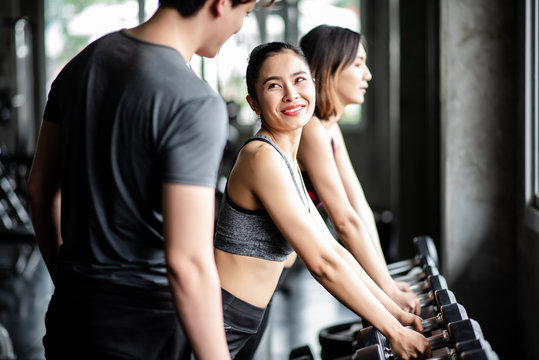 Young healthy woman ligfting dumbbells in the gym with personal trainer