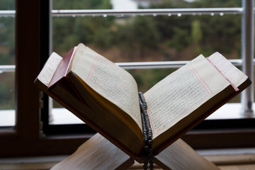 Quran and rosary beads on the wooden background with candle for Islamic concept. Holy book Koran for Muslims holiday, Ramadan,blessed Friday message