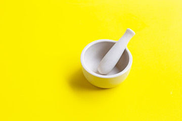 Mortar and pestle on yellow background.